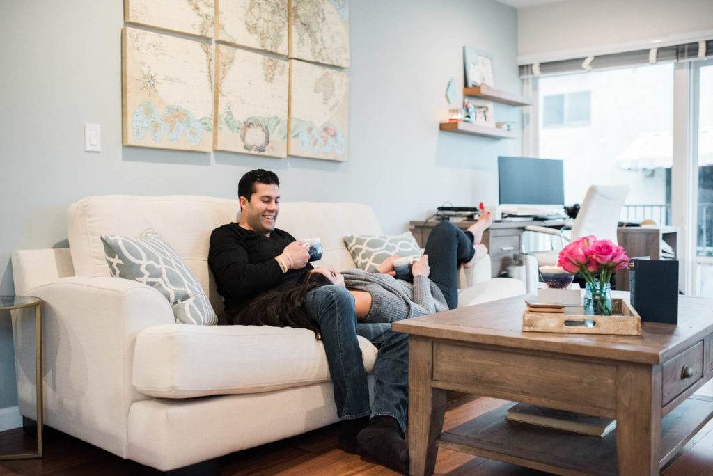 Stay at home date night in ideas. Couple laughing together on the living room couch