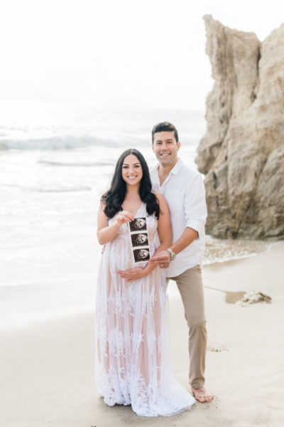pregnancy announcement, couple standing in front of the ocean holding a sonogram